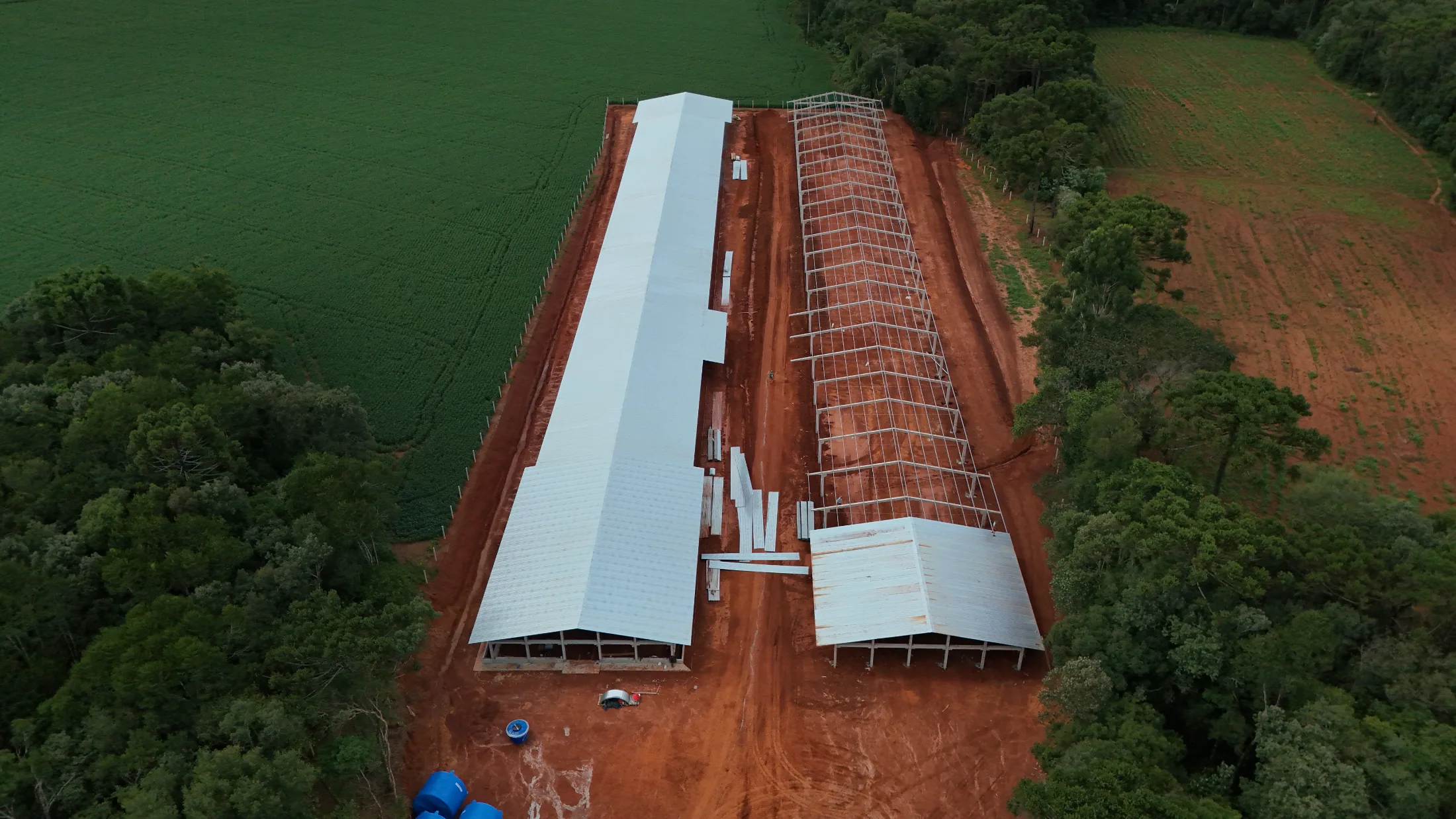 Estrutura pré-moldada de grande porte concluída ao final do dia, com pilares e vigas de concreto em área rural.