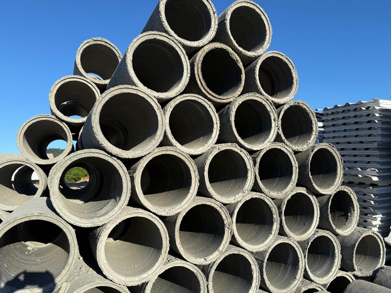 Tubos e palanques de concreto estocados no pátio da fábrica